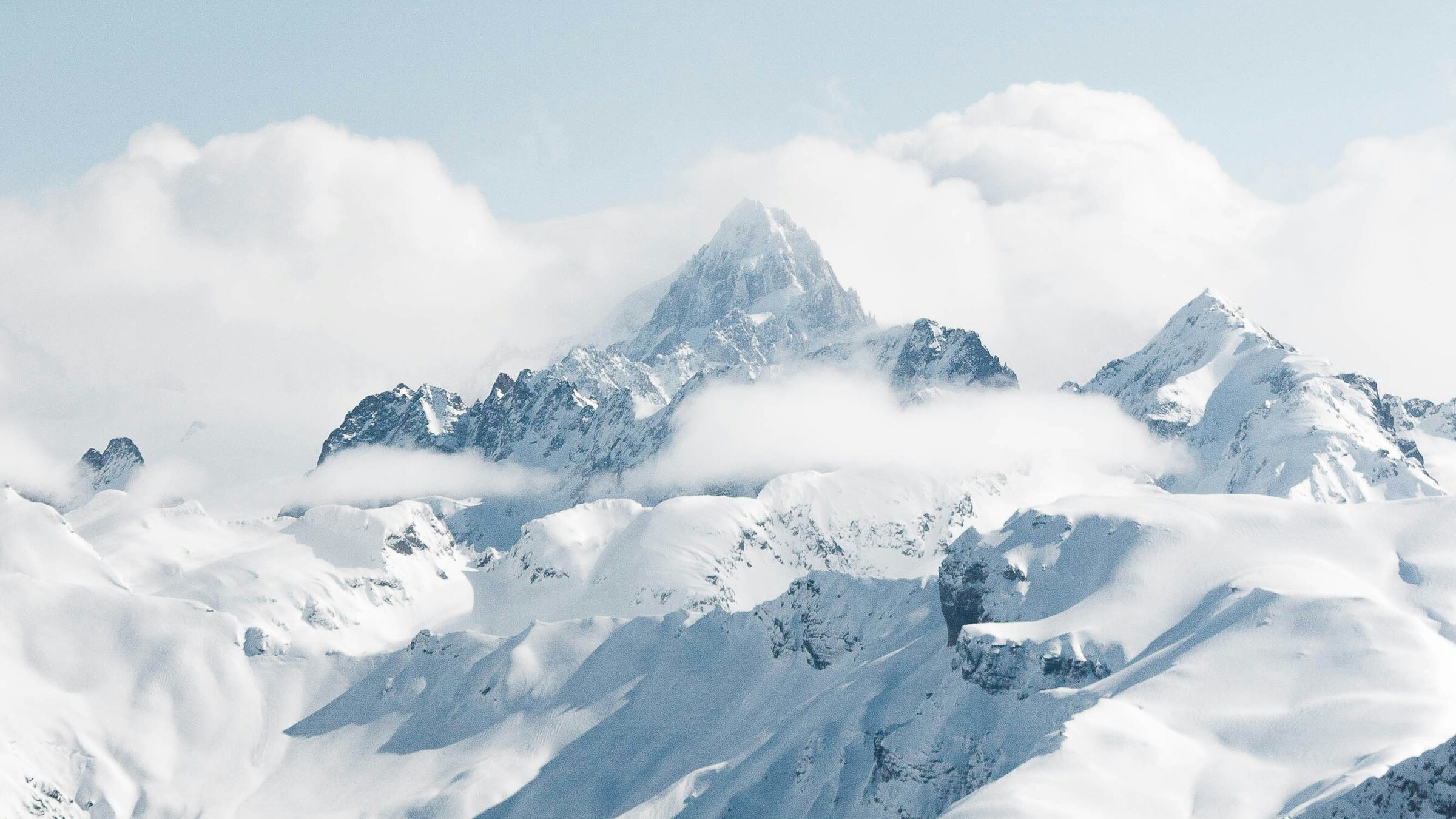 Snow-covered mountain peaks rising through cloud above Samoëns